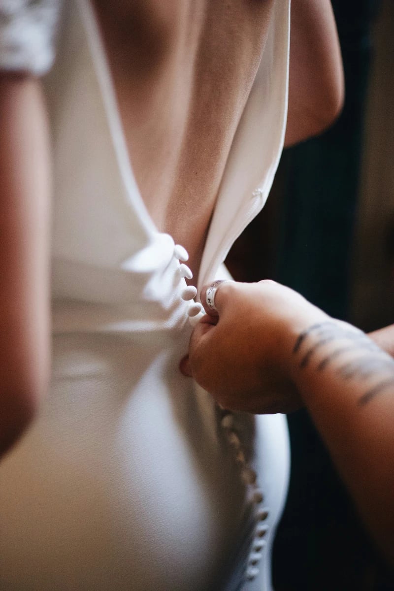Una mano abrochando el traje del novio